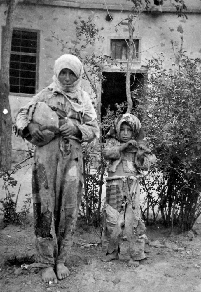 Two in patched rags carry a large round bundle. Harpoot, c. 1919-1922.