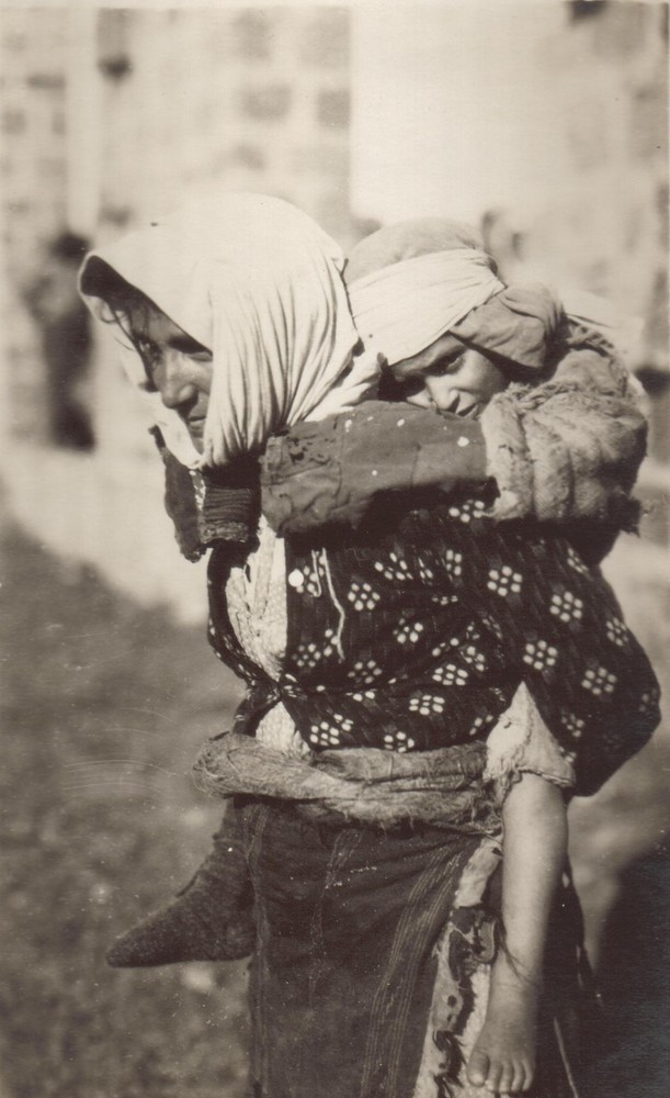A refugee woman carries a child on her back, Beirut, 1922.