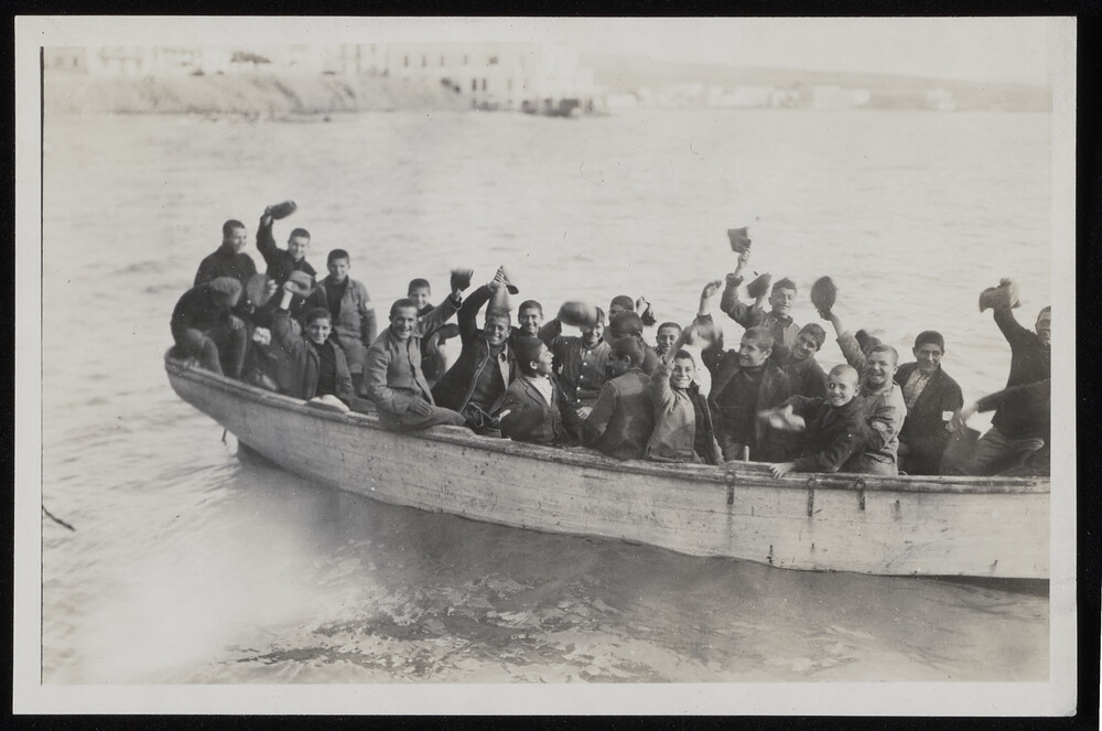 Boys waving caps from a boat, early 1920s