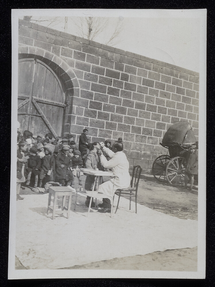 Doctor treating a child's eyes outdoors, Caucasus, 1920s
