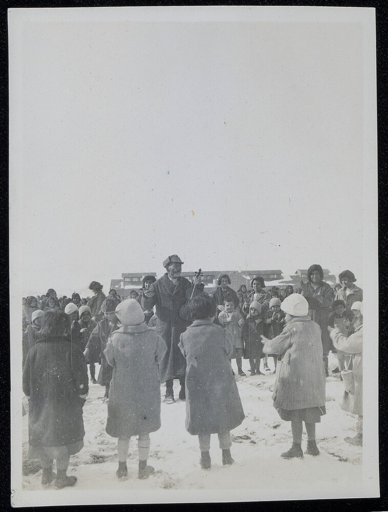 Fiddler ringed by children in the snow, Caucasus, 1920s