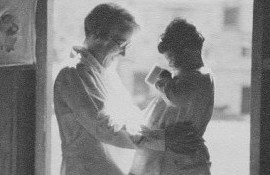 A woman steadies a small girl at an open window.