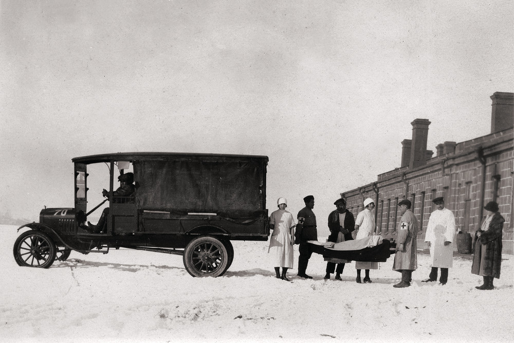 Medical staff carry a stretcher beside an ambulance in the snow.