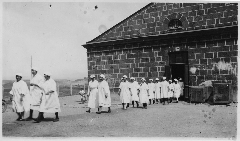 Nurses leave a stone building in a long line.