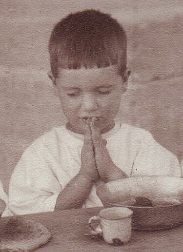 Antranig Karjian says grace over a bowl and tin cup at the Birds' Nest Orphanage, Sidon, c. 1921–1923.