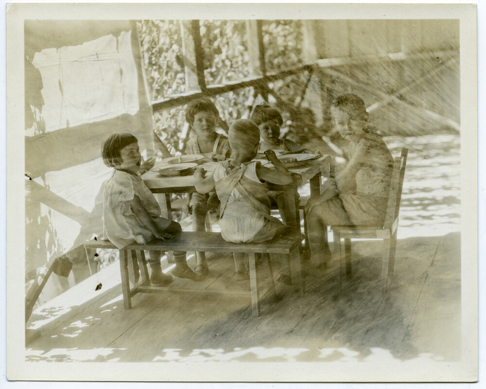 Five children share a meal at a small table on the terrace of the Birds' Nest Orphanage, Sidon, c. 1921–1923.