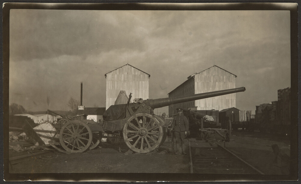 Man standing between artillery cannon and railroad tracks