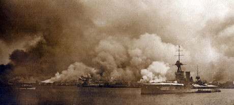 A warship at anchor in Smyrna harbor as the city burns behind it. Vessels from a dozen nations stood by during the catastrophe. September 1922. Image courtesy of the Armenian Genocide Memorial-Institute.