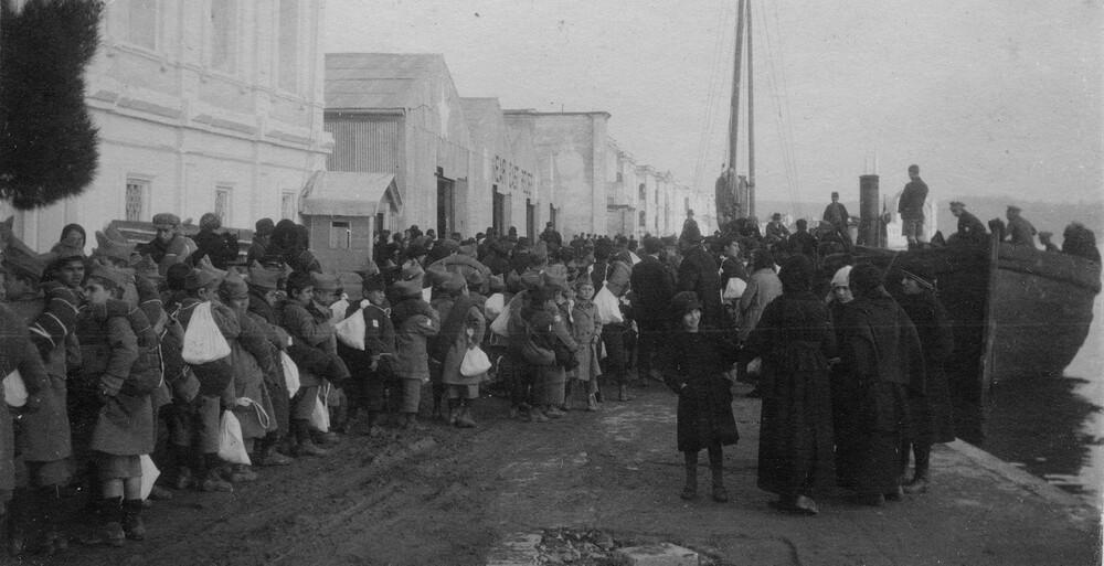 Orphans line up with small bundles of belongings along a Constantinople pier, awaiting transport to Greece in the aftermath of the Smyrna catastrophe, late 1922.