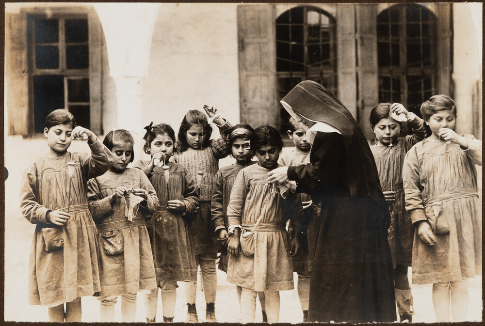 A nun helps a girl with her sewing. Ghazir, 1922.