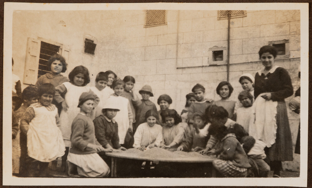 Girls sort wheat on a round tray in the yard. Sidon, 1922.